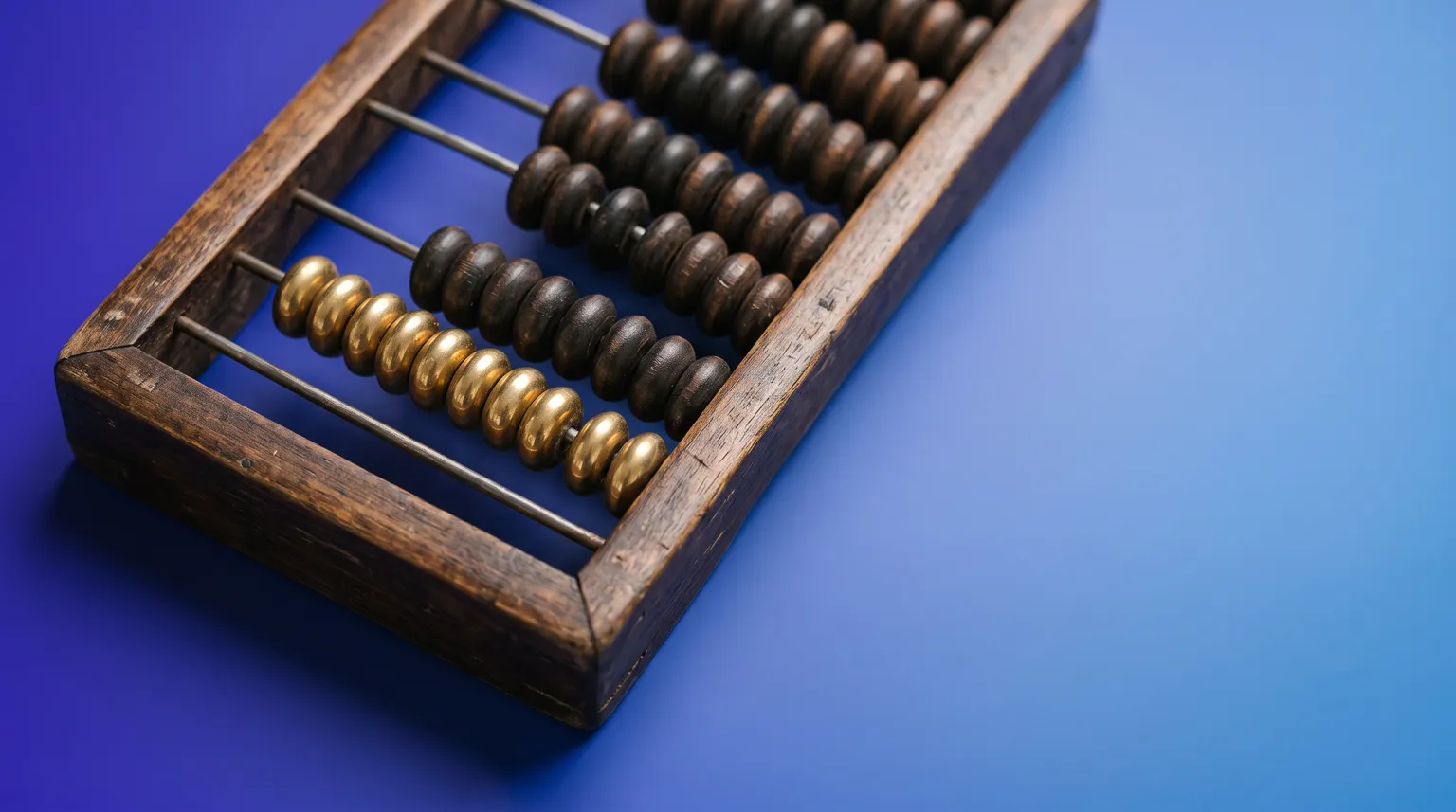 A wooden abacus photographed close up on a deep blue background, one row of beads in polished brass.